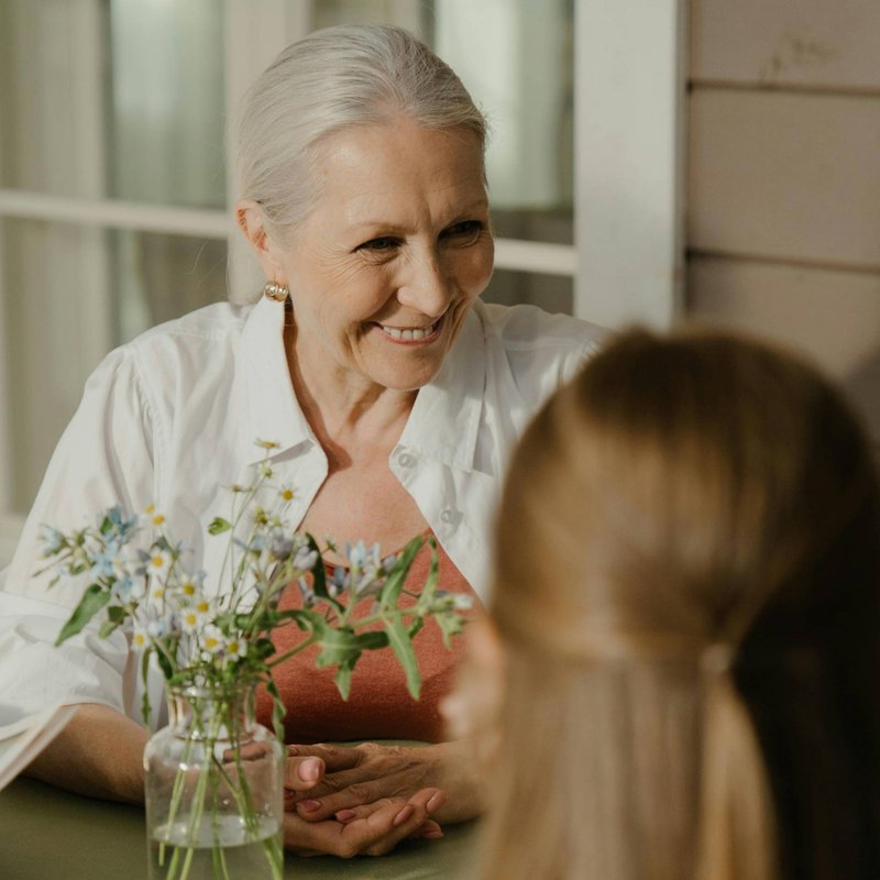 A woman with gray hair smiling with another woman