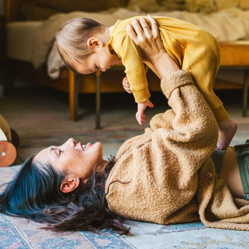 woman lying on the carpet holding her baby up