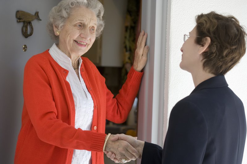 elderly woman greets a door-to-door salesperson