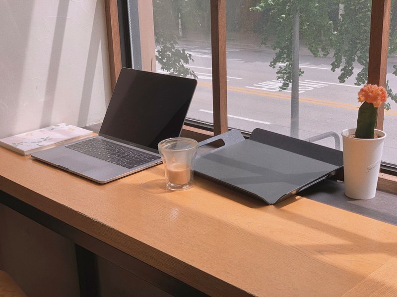 A laptop and a glass of water on a clean table surface, warm light, the minimal elemental setup of someone about to begin building something from nothing