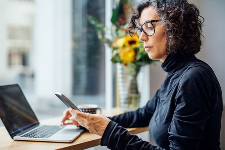 employee reading employee benefits communication on phone and laptop