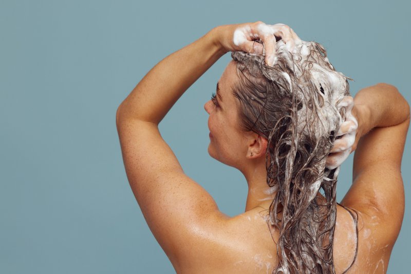 A woman shampooing, with the right products protecting her from scalp conditions.