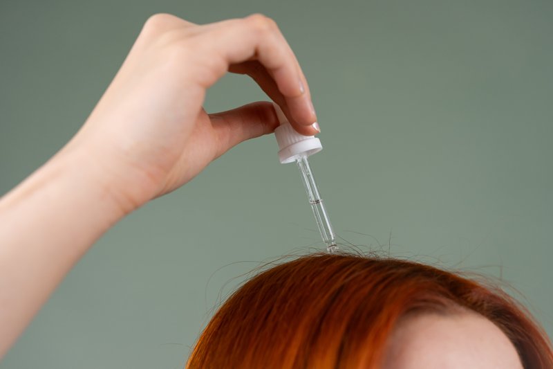A lady applying hair serum to promote healthy scalp.