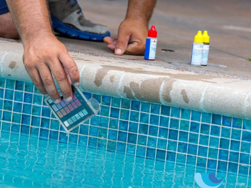 A worker testing the water, since pool chemicals necessitate fiberglass pool resurfacing.