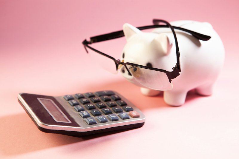 A piggy bank wearing glasses next to a calculator