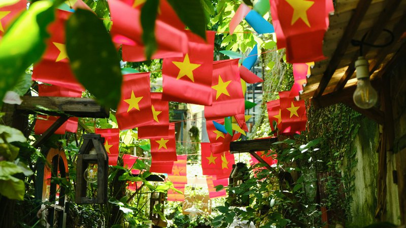 A walkway with many red and yellow flags hanging from the ceiling