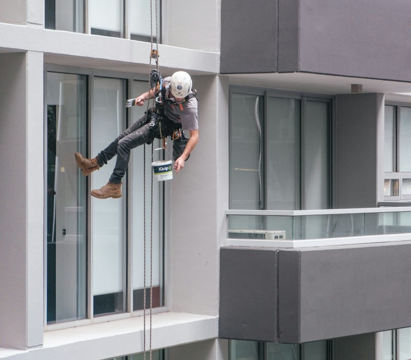 man in black jacket and black pants jumping on window during daytime