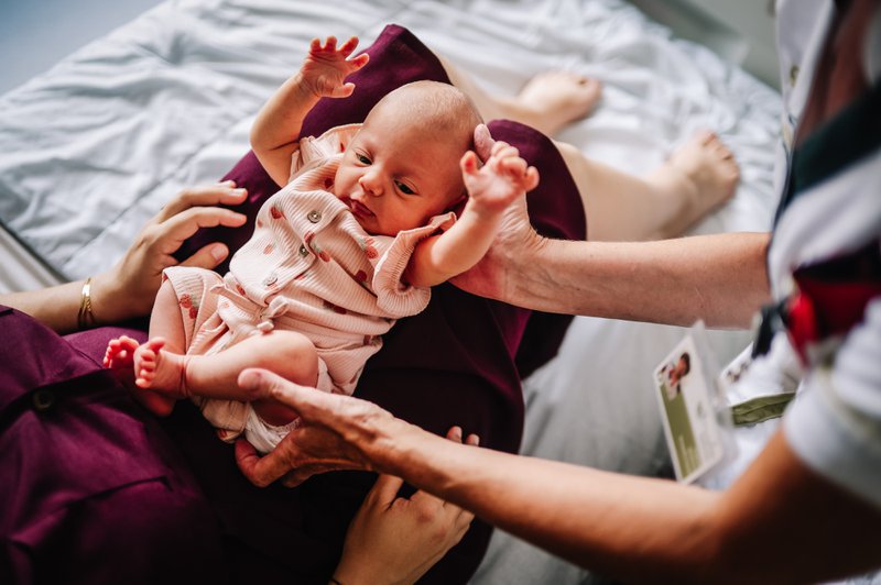 Vroedvrouw legt baby bij mama.