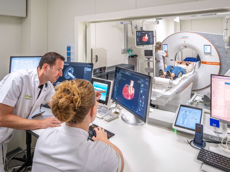 Arts bekijkt CT-beelden op het scherm terwijl de patiënt op de CT-scanner ligt