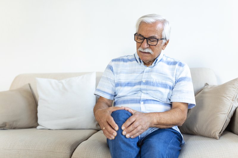 Elderly man with aching knee, seriously considering total knee replacement surgery.