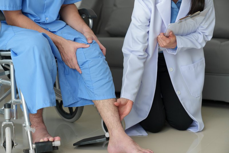 Patient in wheelchair during checkup after knee replacement surgery
