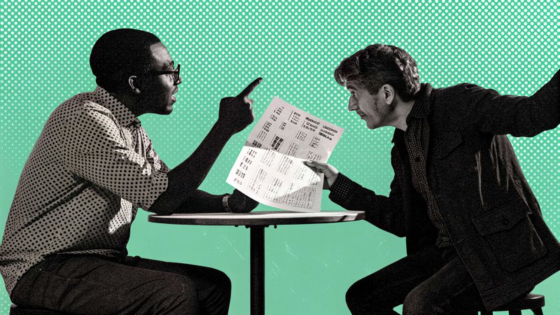 Two people at a small table. One leans in talking with a raised hand while the other reads from a printed sheet instead of listening.
