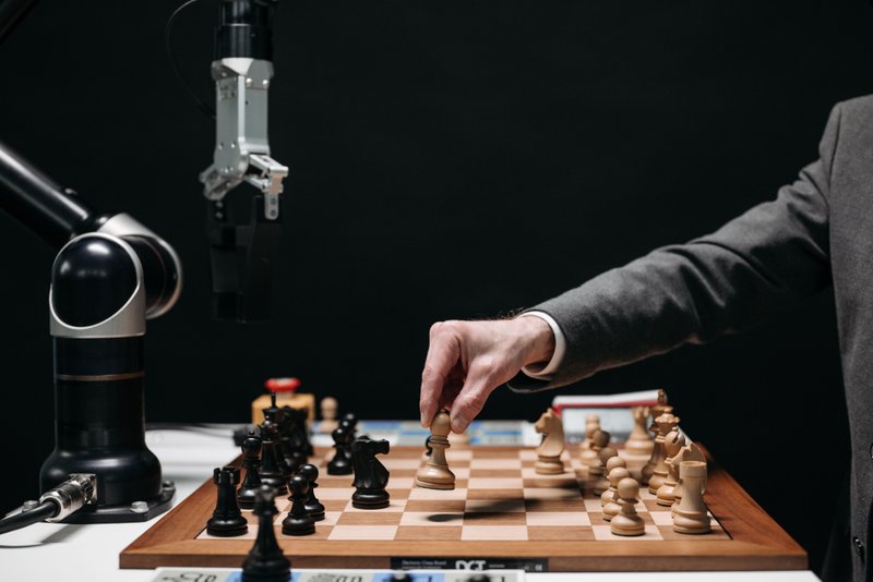 A person playing chess against a robot.
