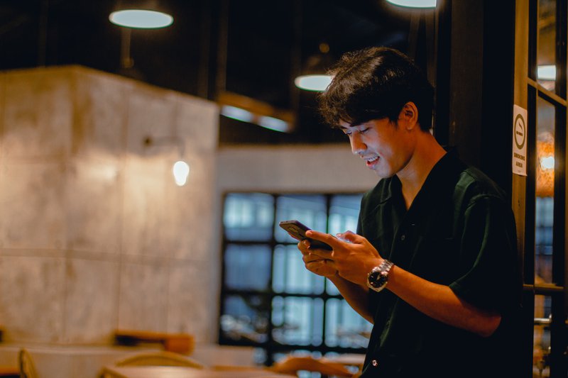 Person using a phone leaning on a glass wall. Mobile UX Design principles