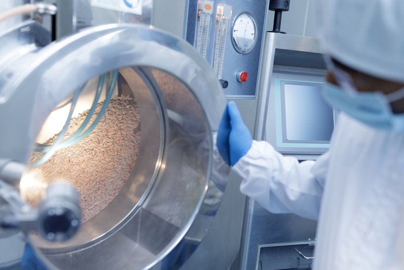 Worker inspecting powder supplement manufacturing capacity of equipment