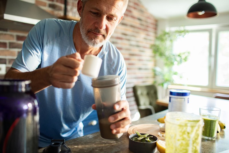 Older man preparing a drink made from powder supplements.