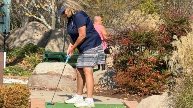 Competitive players in action on an outdoor mini golf course