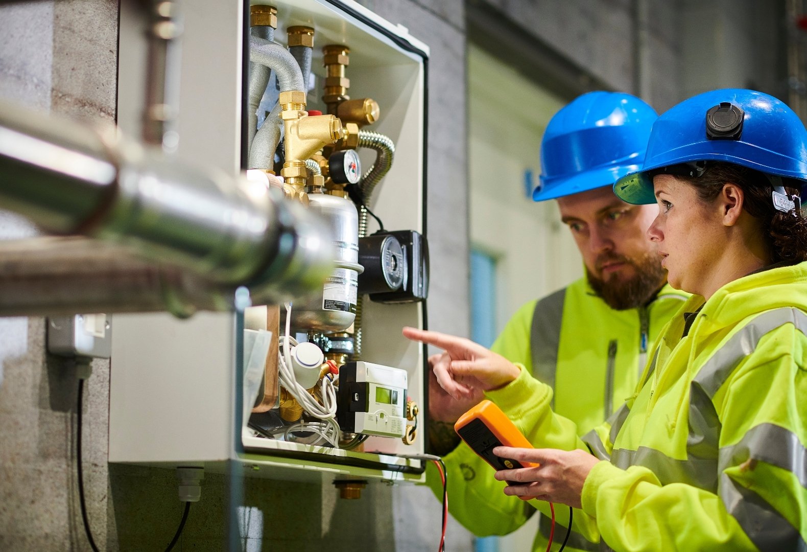 Plumbing technicians inspecting a boiler room.