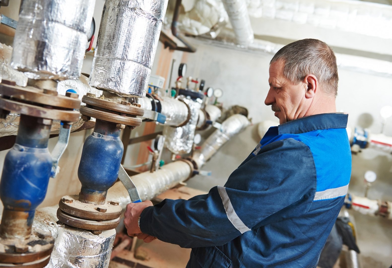 Plumber checking if pipes are keeping up with boiler compliance rules.