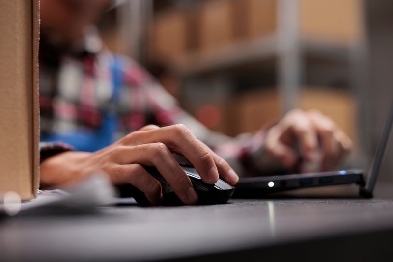 Warehouse employee using computer to fix billing errors.