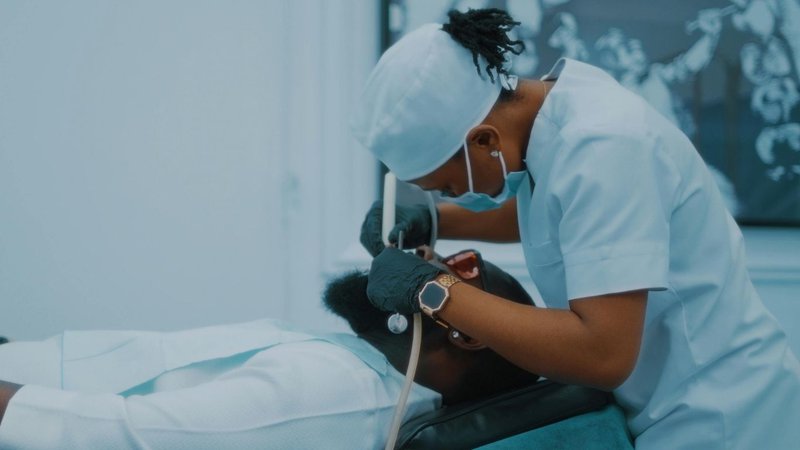 insurance basics for new dentist: A dental professional in scrubs and mask works