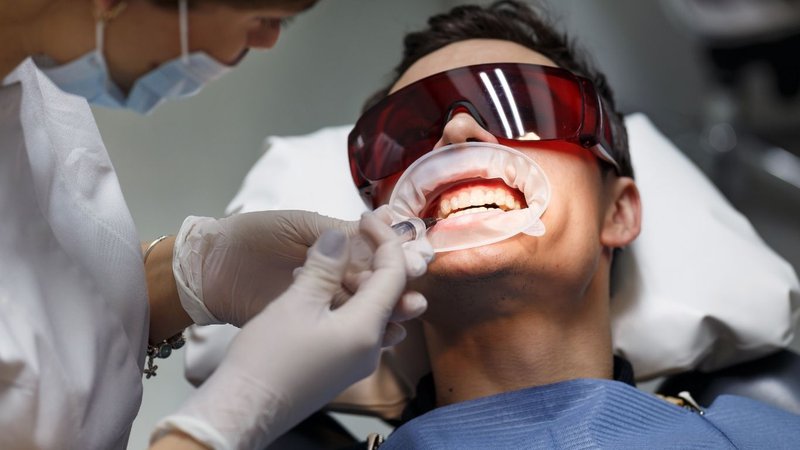 A person wearing red protective glasses and a dental mouth retractor