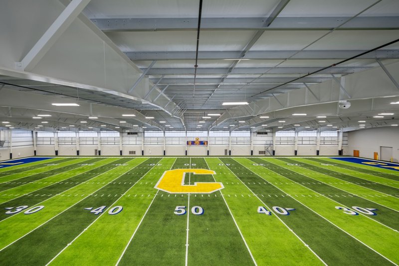 An indoor football field with a clear wall, highlighting athletic facility Polycarbonate Uses.
