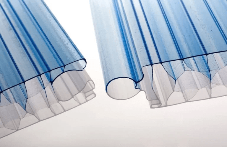 ​This close-up image showcases multiple layers of multiwall polycarbonate sheeting, a popular material for roofing and glazing. The focus is on the edges and the internal structure of the panels.