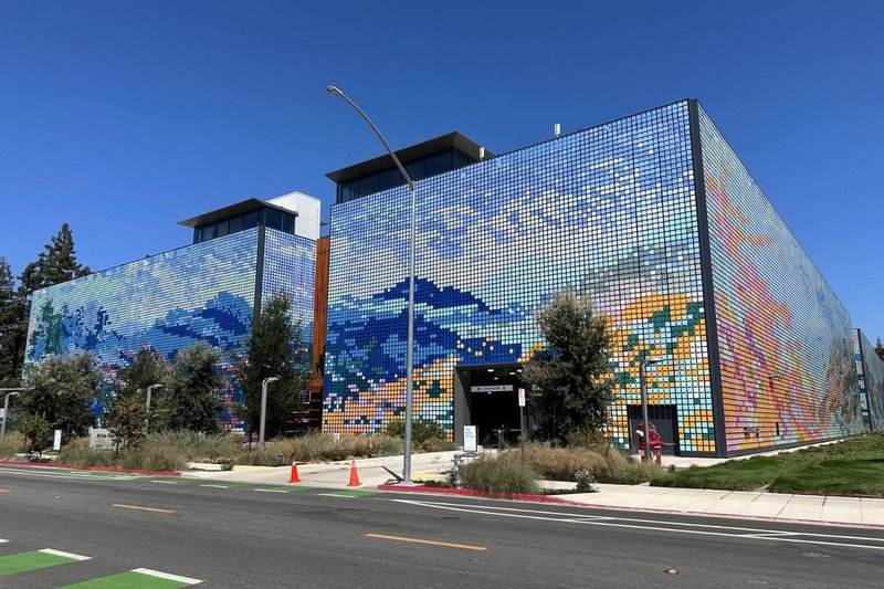 A modern building's kinetic wind wall displaying an abstract mosaic landscape mural.