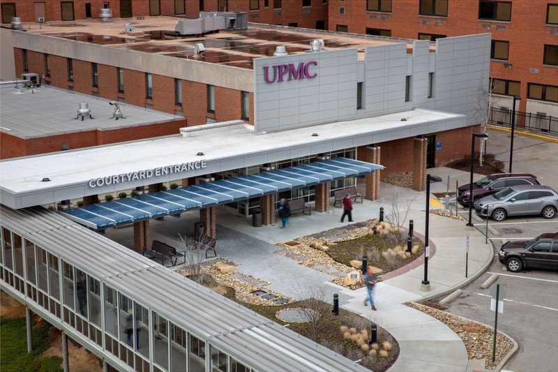 A courtyard entrance featuring a covered walkway with a protective glass canopy.