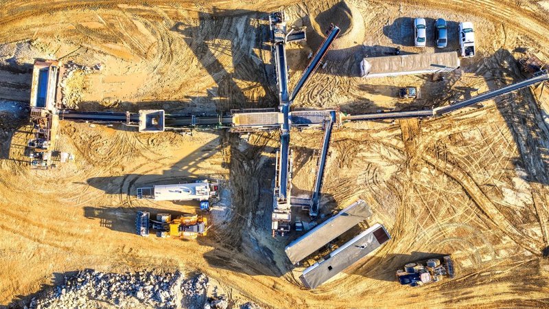 "Aerial view of a high-density industrial site with heavy machinery, showing the ideal placement for a community tornado shelter.
