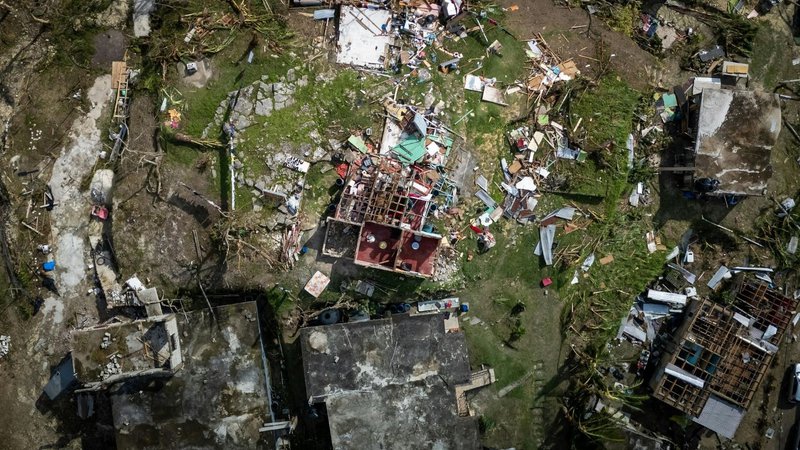 Drone footage of destroyed buildings and scattered debris, illustrating the environmental risks that mobile shelters are designed to withstand.