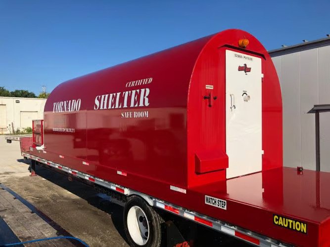 A mobile Red Dog emergency safe room loaded on a transport trailer and prepared for delivery to a high-risk industrial site.