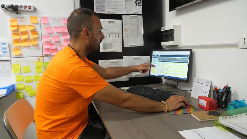 A logistics administrator managing shipping schedules on a computer for paper logistics.