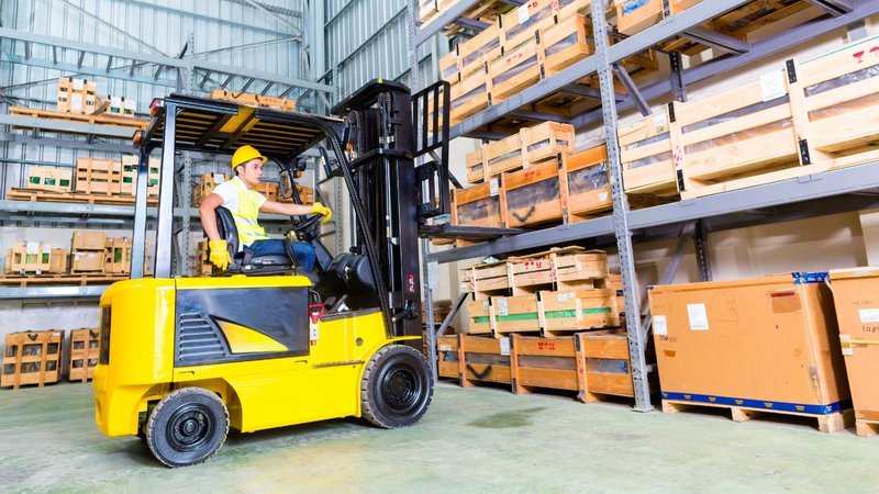 A warehouse employee driving a forklift, an industrial equipment item evaluated for the useful life of assets.