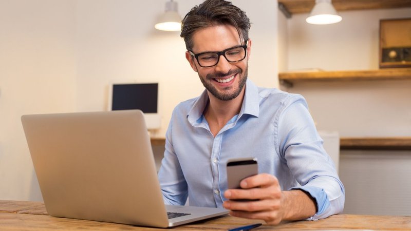 A man smiling while checking real-time inventory updates on a stock alerts app.