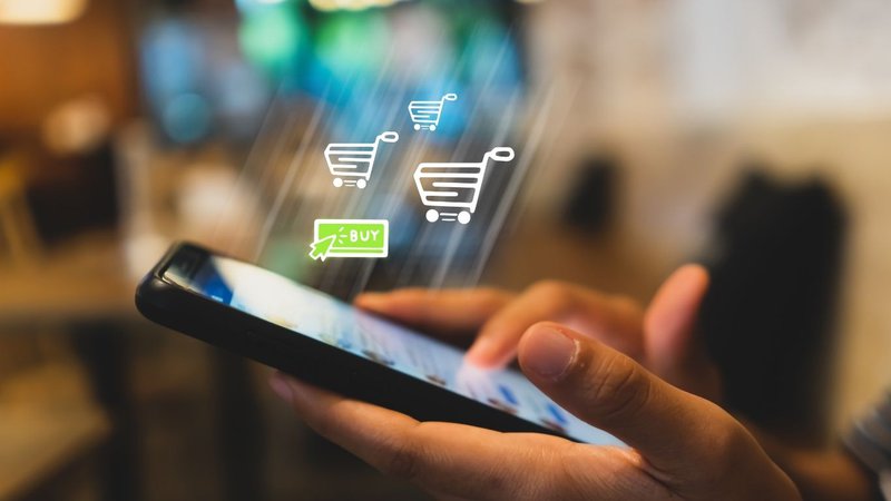 Hands holding a smartphone with shopping icons prompted by a stock alerts app.