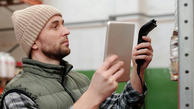 A warehouse employee managing inventory with a tablet and scanners used in warehouses.