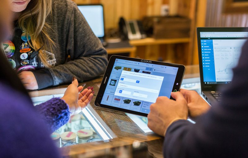 a group of people discussing business while holding a laptop
