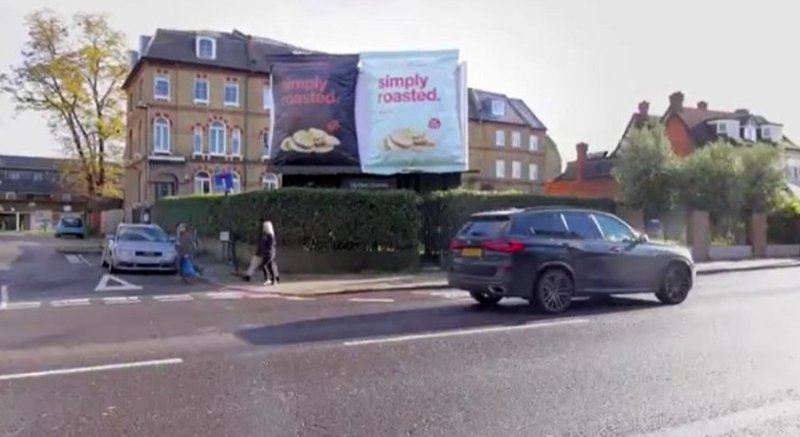 A roadside billboard advertisement displayed near local traffic and pedestrians.