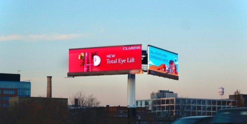 A large dual billboard displays positioned above a city roadway for broad market visibility.
