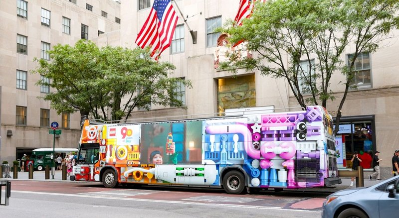 A colorful bus advertising wrap shown on a busy city street.