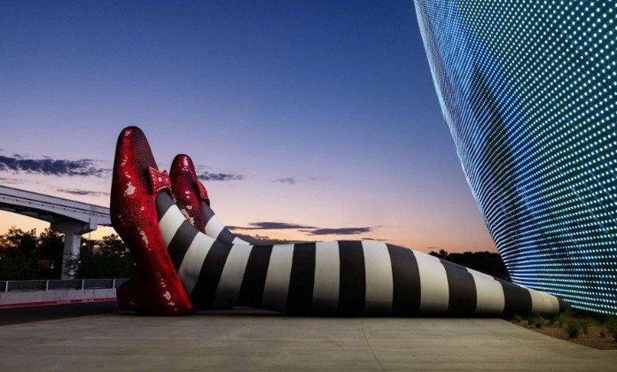 An oversized 3D shoe installation beside a digital display showing bold billboard creative services