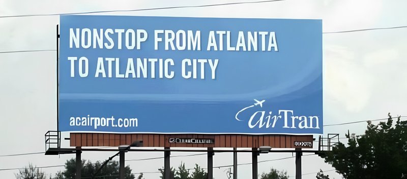 An atlanta highway billboard with text Nonstop from Atlanta to Atlantic city positioned along a major airport travel route