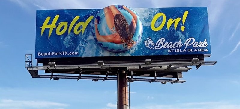 A static billboard advertising Beach Park at Isla Blanca displayed against a clear blue sky, showing how much does a billboard cost in a real outdoor placement.