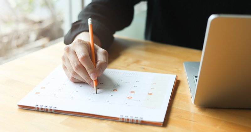 A person planning campaign timing on a calendar to align advertising in Cobb County with seasonal family purchase decisions.