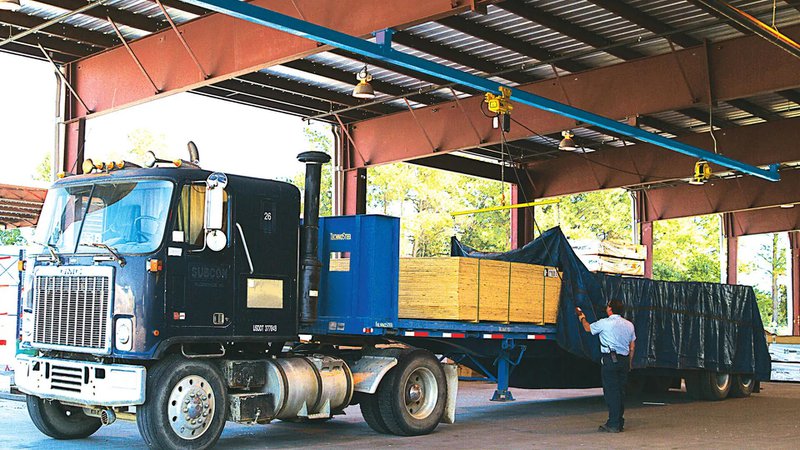 This photo features a worker using an overhead tarping system to cover cargo