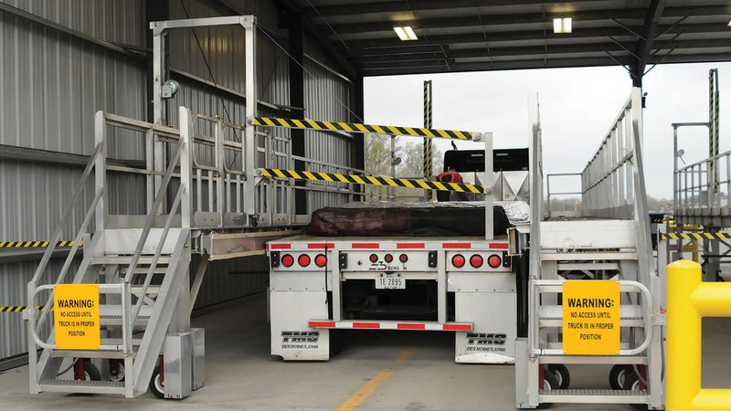 This photo features a flatbed tarping platform with a truck parked inside