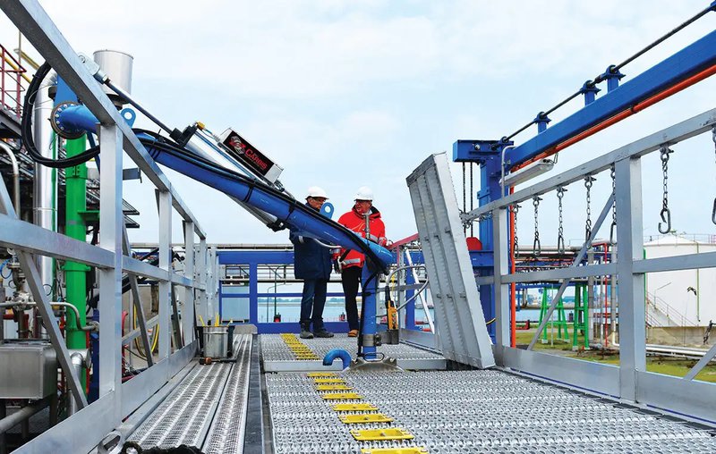 Two workers walking on an access platform with an integrated loading arm