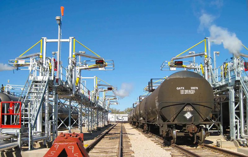 A railcar platform outfitted with loading arms and fall protection guardrails